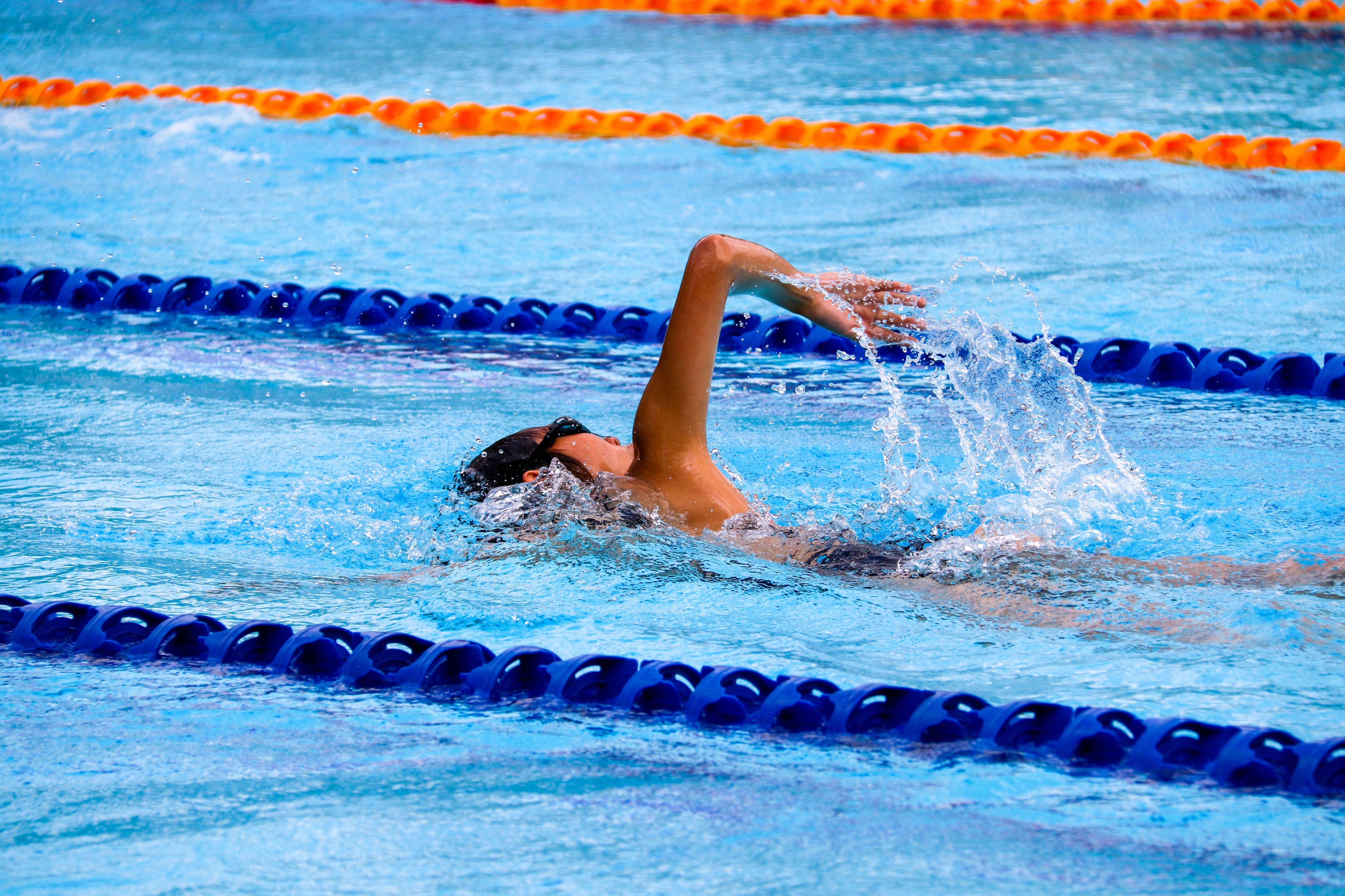 Swimmer in the pool performing freestyle stroke, extending one arm forward with a steady breathing rhythm.